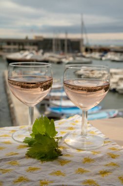 Açık terasta sunulan Rose Provencal şarabı Cassis, Provence, Fransa 'da renkli tekneleri olan eski balıkçıların limanına bakıyor.