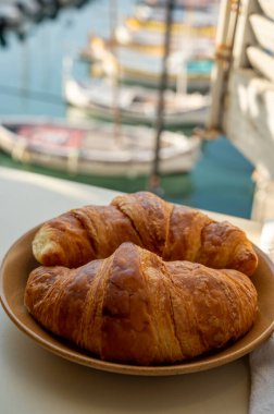 Provence 'de yaz sabahı, taze kruvasanlarla geleneksel kahvaltı ve Cassis, Provence, Fransa' daki balıkçı teknelerinin manzarası.