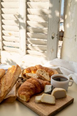 Fransız kahvaltısında taze kruvasan, baquett ekmeği, crottin keçi peyniri, sade kahve ve Cassis, Provence, Fransa 'daki balıkçı tekneleri manzaralı. Provence 'de Tatil.
