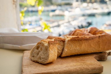 Provence 'de yaz sabahı, taze kruvasan ve baget ekmeği ile geleneksel kahvaltı Cassis, Provence, Fransa Limanı' ndaki balıkçı teknelerinin manzarası.