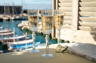 Üç bardak Fransız şampanyası köpüklü şarap ve renkli balıkçı teknelerinin manzarası Cassis, Provence, Fransa 'daki eski limanda, yaz partisinde