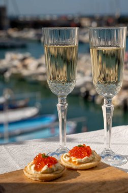 Ekşi krema ve tuzlu somon kırmızısı havyar ve Fransız şampanyası brut köpüklü şarap ile küçük krep çiftleri Cassis, Provence, Fransa 'nın limanındaki renkli teknelerde servis edilir.