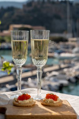 Ekşi krema ve tuzlu somon kırmızısı havyar ve Fransız şampanyası brut köpüklü şarap ile küçük krep çiftleri Cassis, Provence, Fransa 'nın limanındaki renkli teknelerde servis edilir.