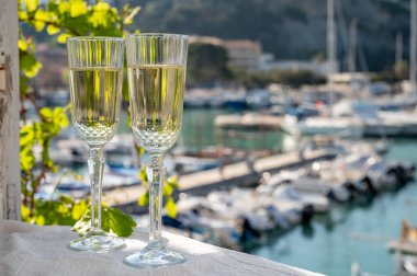 İki bardak Fransız şampanyası, köpüklü şarap ve renkli balıkçı teknesiyle Cassis, Provence, Fransa 'daki eski limanda öğle yemeği.