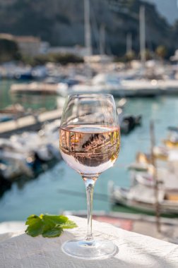 Açık terasta sunulan Rose Provencal şarabı Cassis, Provence, Fransa 'daki eski balıkçıların limanında renkli teknelerle servis ediliyor.