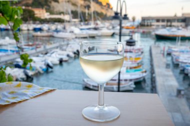 Cassis şarap üretim bölgesinden gelen soğuk beyaz şarap, Fransa, Provence, Cassis 'te renkli tekneleri olan eski balıkçıların limanına bakan terastaki camlarda servis edilir.