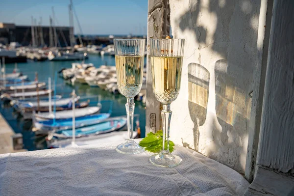 Birthday celebration in summer with two glasses of French champagne sparkling wine and view on colorful fisherman's boats in old harbour in Cassis, Provence, France