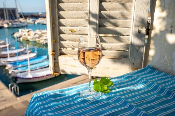 Açık terasta sunulan Rose Provencal şarabı Cassis, Provence, Fransa 'daki eski balıkçıların limanında renkli teknelerle servis ediliyor.