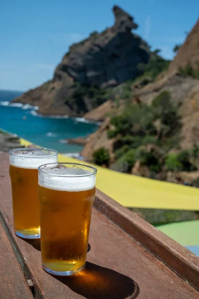 Two glasses of fresh cold lager beer served outdoor in snack bar with view on Calanque de Figuerolles in La Ciotat, Provence, France in sunny day