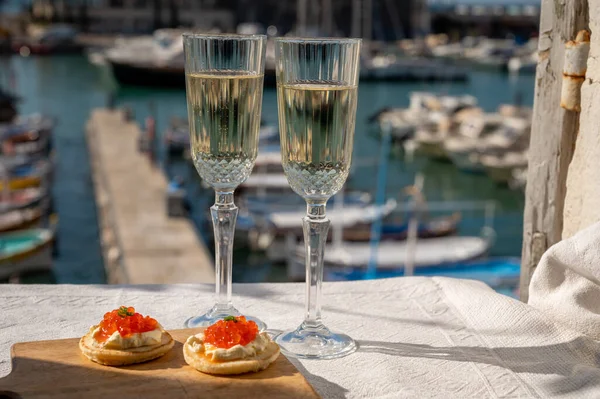 Ekşi krema ve tuzlu somon kırmızısı havyar ve Fransız şampanyası brut köpüklü şarap ile küçük krep çiftleri Cassis, Provence, Fransa 'nın limanındaki renkli teknelerde servis edilir.