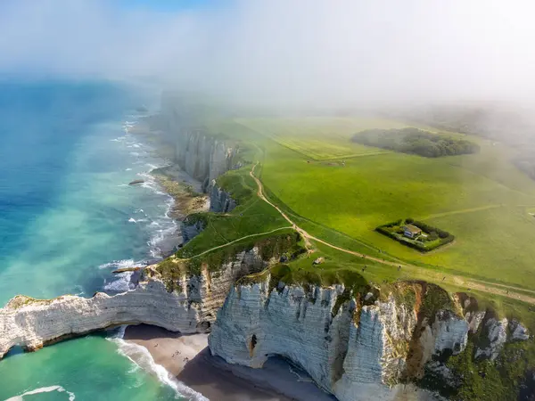 Etretat 'taki Porte d' Aval kemeri yakınlarındaki tebeşir kayalıklarındaki Aerian manzarası yeşil çayırlar ve kıyı şeridi ve Atlantik Okyanusu 'nun mavi suyu, Normandiya, Fransa. Turistler için tatil yeri.