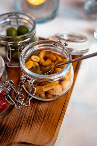 Glass jars with healthy party snacks served in bar, tasty appetisers cherry tomatoes, oliver asnd pinda nuts
