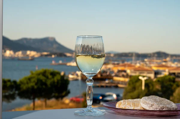 Glass of dry French wine and soft goat cheese from Provence and view on Toulon sea harbour, France