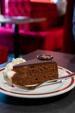 Meşhur Sachertorte çikolatalı pastası. Kayısı reçeli ve beyaz tahtada krem şanti ile servis ediliyor.