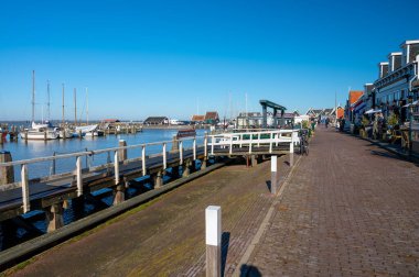 Hollanda 'nın küçük Marken kasabasında güneşli bir bahar gününde eski Hollanda, Hollanda' da bulunan ahşap evlerle yürüyorum.