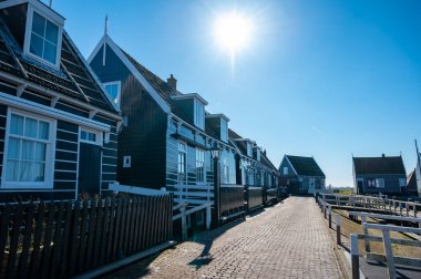 Hollanda 'nın küçük Marken kasabasında güneşli bir bahar gününde eski Hollanda, Hollanda' da bulunan ahşap evlerle yürüyorum.