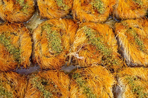 Turkish or arabic sweet dessert, baklava burma kadayif made from filo pastry, filled with chopped pistachio nuts and sweetened with syrup or honey, close up