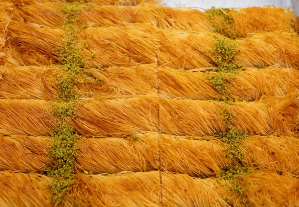 Turkish or arabic sweet dessert, baklava burma kadayif made from filo pastry, filled with chopped pistachio nuts and sweetened with syrup or honey, close up