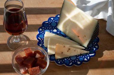 İspanyol sert manchegosu, inek, koyun ve keçi peyniri açık havada membrillo reçeli ve bir bardak şeri şarabı ile servis edilir. Mavi Endülüs stil panosunda. Kapatın.