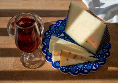 İspanyol sert manchegosu, inek, koyun ve keçi peyniri açık havada membrillo reçeli ve bir bardak şeri şarabı ile servis edilir. Mavi Endülüs stil panosunda. Kapatın.