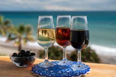 Tasting of Spanish sweet and dry fortified Vino de Jerez sherry wine and green olives with view on blue sea and beach near El Puerto de Santa Maria, Andalusia, Spain clipart