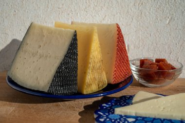 İspanyol sert manchegosu, inek, koyun ve keçi peyniri açık havada, mavi Endülüs stili tahtasında güneş ışığında membrillo reçeli servis edilir.