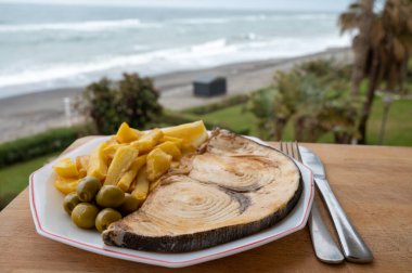 Deniz ürünleri tabağı deniz manzaralı, kıIıçbalığından ızgara biftek ya da patates kızartması ve yeşil zeytinle servis edilen spada, yakın çekim.