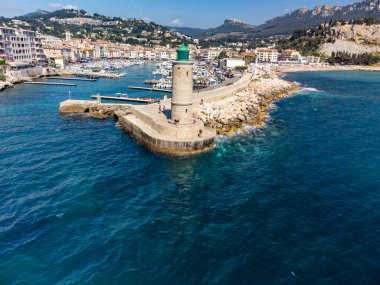 Kumsalda panoramik hava manzarası, mavi deniz, uçurumlar, evler, sokaklar ve Cassis, Provence, Fransa 'da deniz feneri olan eski balıkçıların limanı bulutlu bir günde