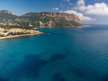 Kumsalda panoramik hava manzarası, mavi deniz, uçurumlar, evler, sokaklar ve Cassis, Provence, Fransa 'da deniz feneri olan eski balıkçıların limanı bulutlu bir günde