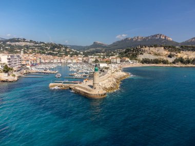 Kumsalda panoramik manzara, mavi deniz, uçurumlar, evler, sokaklar ve bulutlu bir günde Cassis, Provence, Fransa 'da deniz feneriyle eski balıkçıların limanı