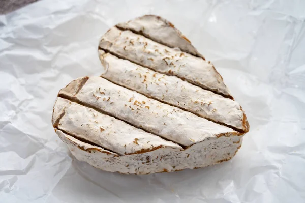 French farmers heartshaped neufchatel cow cheese with mold on white paper, Normandy, France