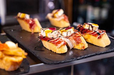 Bask Ülkesi ve Navarre 'ın tipik aperatifleri, Pinchos ya da pinktolar, barda yemeye hazır, soslu ya da malzemeli küçük dilimler, San Sebastian, İspanya, kapatın.