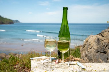 Tasting of txakoli or chacol slightly sparkling very dry white wine produced in Spanish Basque Country, served outdoor with view on Bay of Biscay, Atlantic Ocean clipart