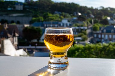 Arka planda Etretat köyü, Normandiya, Fransa 'da güneş ışığı ve evlerinde bir bardak elma şarabı içilir.