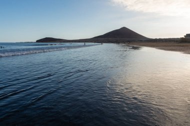 Tenerife Adası, İspanya 'nın güneyindeki El Medano' da kumlu sahilde gün batımında dinleniyorum.