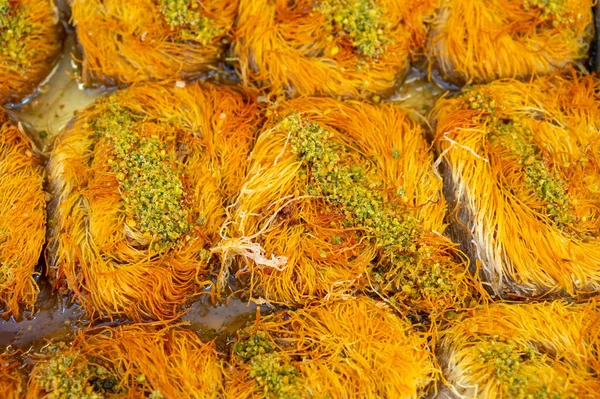 Turkish or arabic sweet dessert, baklava burma kadayif made from filo pastry, filled with chopped pistachio nuts and sweetened with syrup or honey, close up