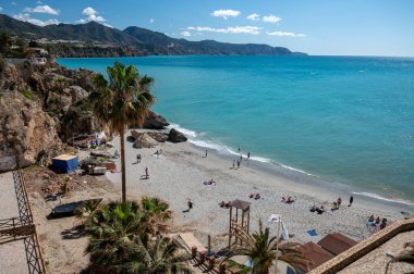 Seyahat yeri, kumlu sahil manzarası, mavi deniz ve dağlar Endülüs 'ün küçük bir kasabası olan Nerja' daki Balcon de Europa 'dan ilkbaharda Costa del Sol, İspanya' da beyaz evleri ve dar sokakları olan