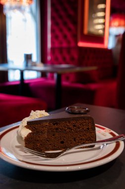 Meşhur Sachertorte çikolatalı pastası. Kayısı reçeli ve beyaz tahtada krem şanti ile servis ediliyor.