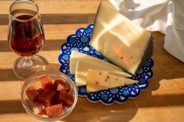 İspanyol sert manchegosu, inek, koyun ve keçi peyniri açık havada membrillo reçeli ve bir bardak şeri şarabı ile servis edilir. Mavi Endülüs stil panosunda. Kapatın.