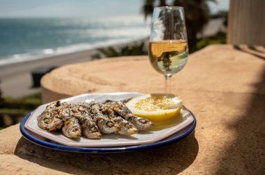 Sardalyalar şişler ve şöminede zeytin ağaçlarıyla hazırlandı, limon ve bir bardak sonlu şarapla servis edildi ve mavi deniz manzaralı, Malaga, Endülüs, İspanya 'da yaz tatili