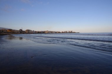 Tenerife Adası, İspanya 'nın güneyindeki El Medano' da kumlu sahilde gün batımında dinleniyorum.