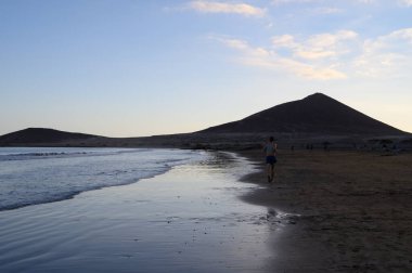 Tenerife Adası, İspanya 'nın güneyindeki El Medano' da kumlu sahilde gün batımında dinleniyorum.