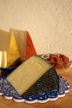 İspanyol sert manchegosu, inek, koyun ve keçi peyniri açık havada, mavi Endülüs stili tahtasında güneş ışığında membrillo reçeli servis edilir.