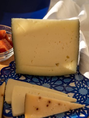 İspanyol sert manchegosu, inek, koyun ve keçi peyniri açık havada, mavi Endülüs stili tahtasında güneş ışığında membrillo reçeli servis edilir.