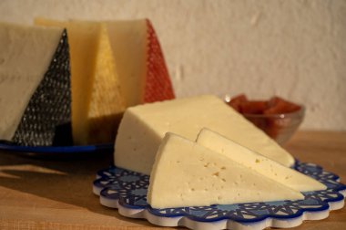 İspanyol sert manchegosu, inek, koyun ve keçi peyniri açık havada, mavi Endülüs stili tahtasında güneş ışığında membrillo reçeli servis edilir.