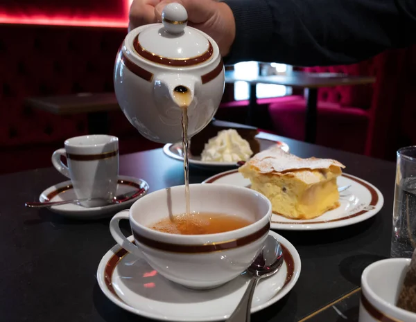 Tea time in England, pouring of black earl grey tea with bergamot in cup, high tea served cafe in London, close up