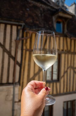 Tasting of white grand cru classe chablis wine with old French houses on background, Burgundy, wine tour is France