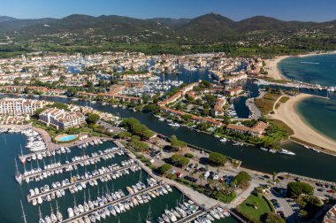 Aerial view on blue water of Gulf of Saint-Tropez, sail boats, houses of Port Grimaud and Port Cogolin, summer vacation in Provence, France