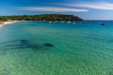 Saint-Tropez yakınlarındaki efsanevi Pampelonne plajı ve mavi deniz manzarası Fransız Rivierası 'nın beyaz kumlu sahillerinde yaz tatili.