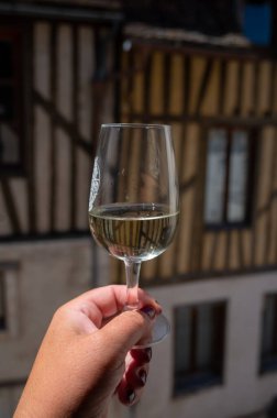 Tasting of white grand cru classe chablis wine with old French houses on background, Burgundy, wine tour is France